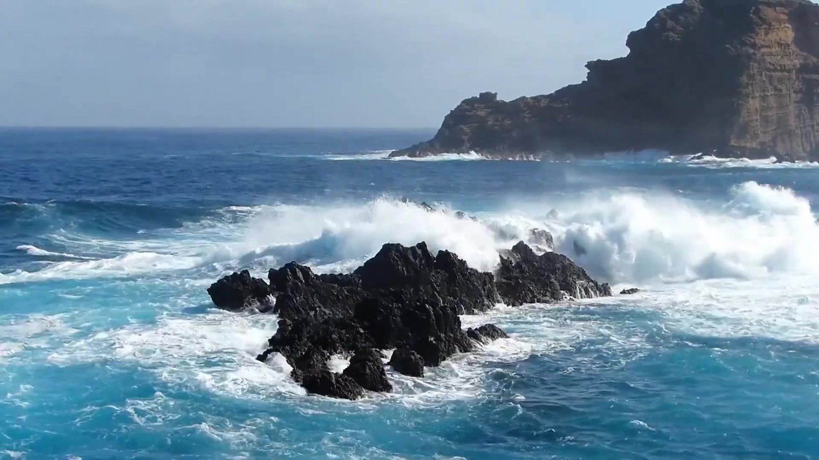 Atlantic waves crashing on black lava rocks in Madeira