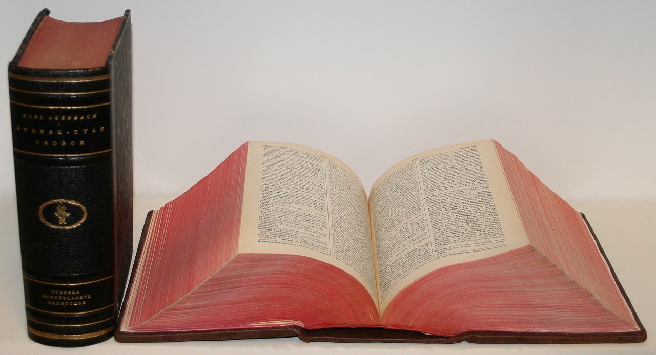 Two Carl Auerbach dictionaries: a Swedish-German volume standing upright and a German-Swedish volume lying open, with red-edged pages