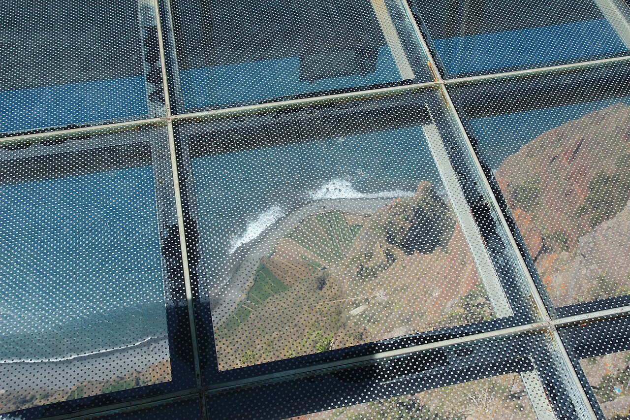 Looking down through the glass floor of the Cabo Girão skywalk in Madeira to the cultivated fields at the foot of the cliff