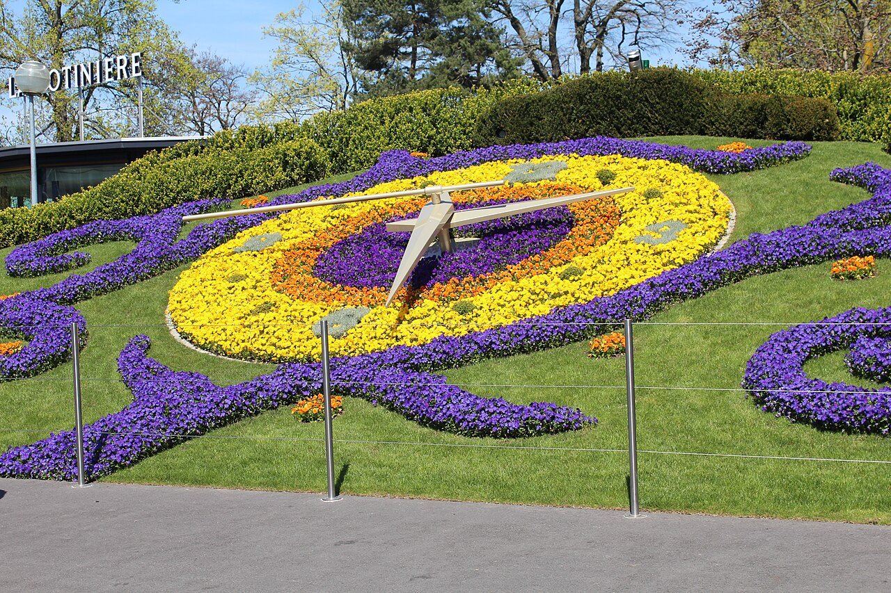 The flower clock in the Jardin Anglais, Geneva: a large clock face of yellow and purple flowers on a lawn, with metal hands