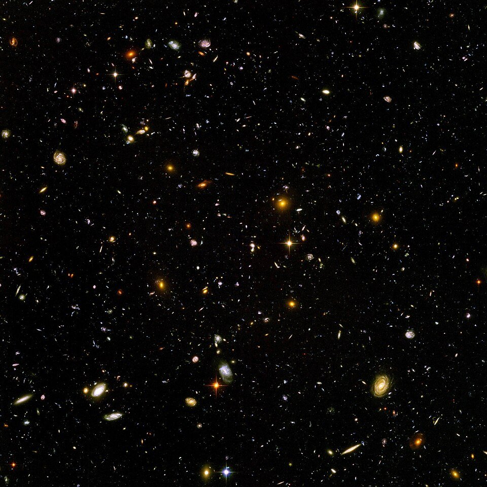 The Hubble Ultra Deep Field: thousands of distant galaxies of many shapes and colours, spirals, ellipticals and faint red specks, scattered across a black sky