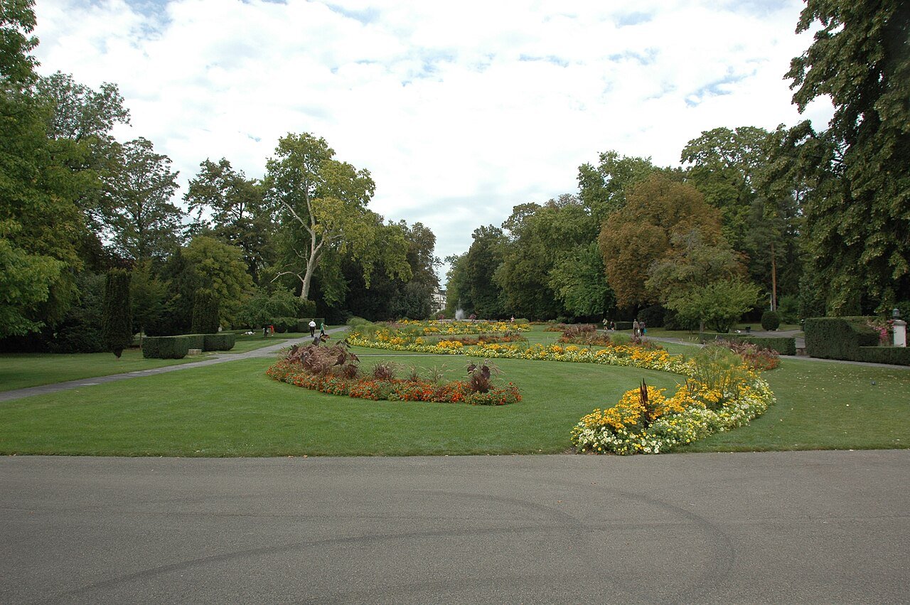 Parc Mon Repos in Geneva: wide lawns, flower beds and tall trees beside a path