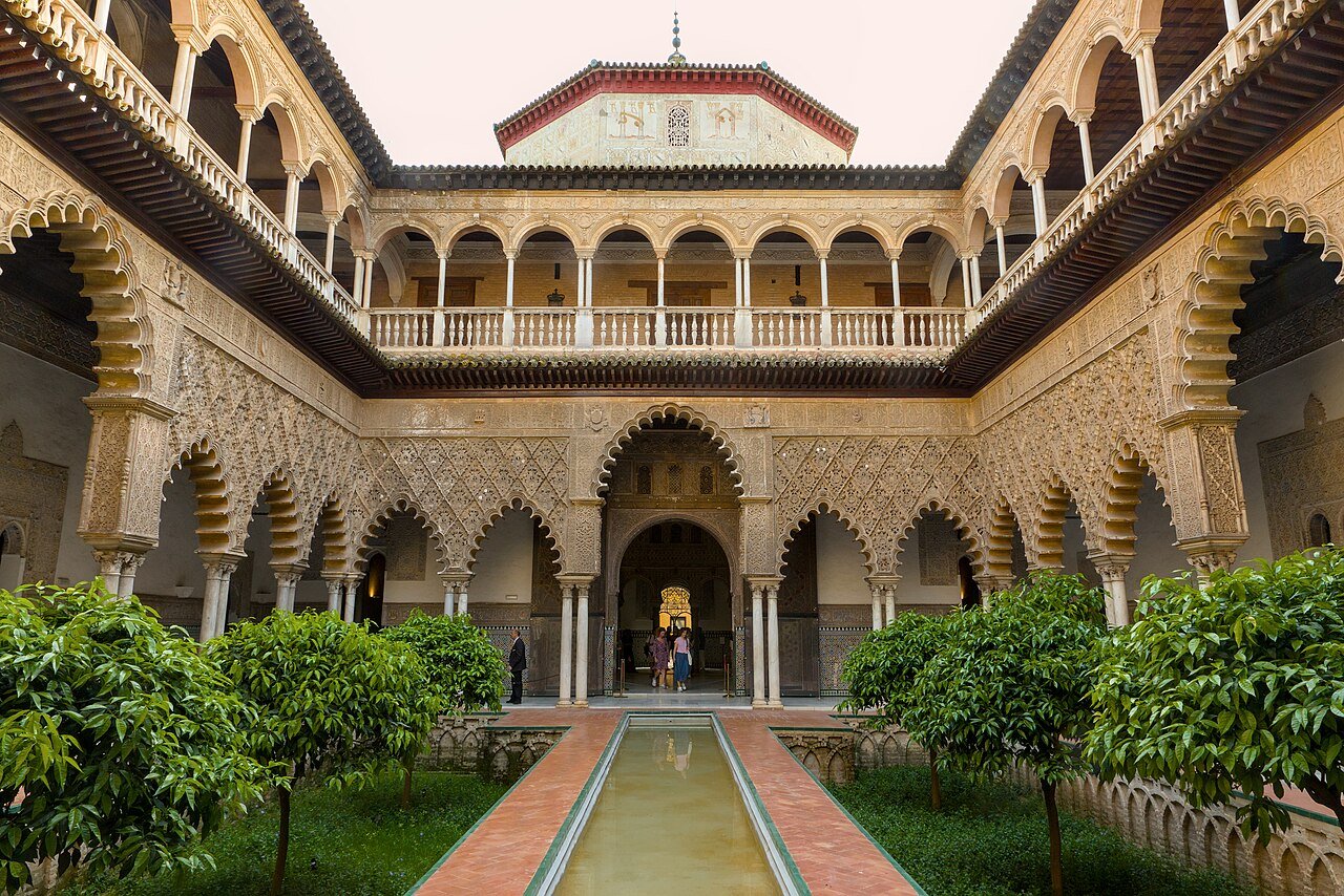 The Patio de las Doncellas in the Royal Alcázar of Seville: a long pool between sunken gardens, framed by carved arches