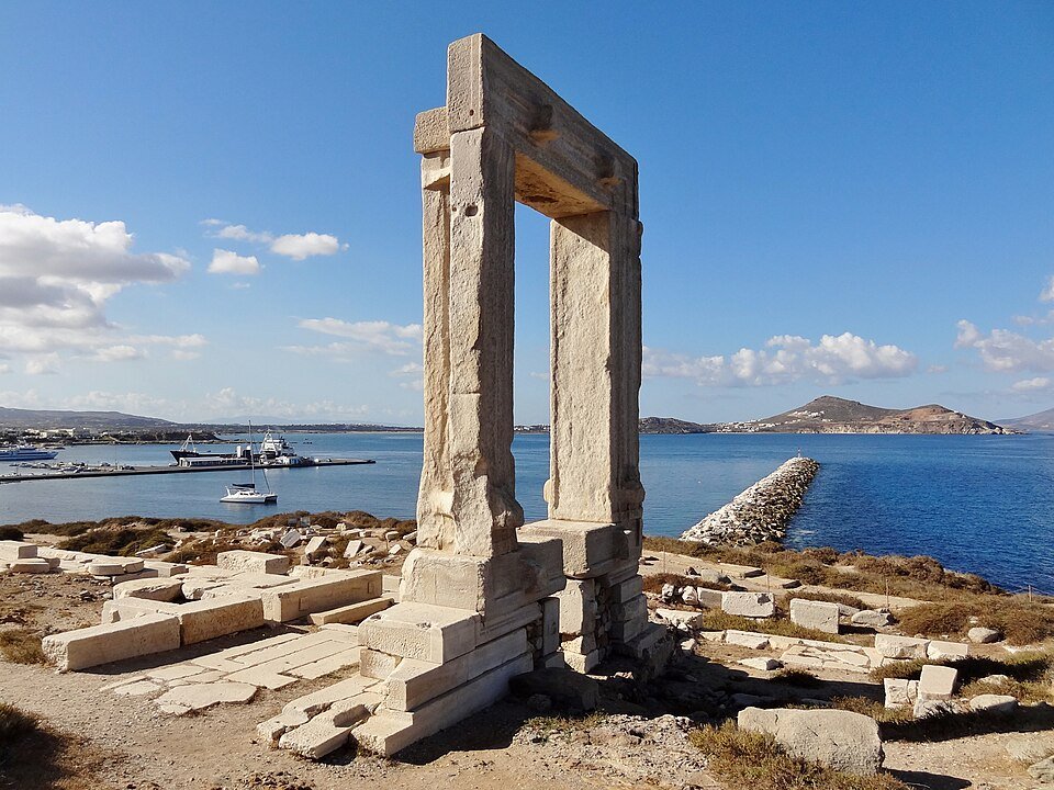 The Portara, a tall marble doorframe of an unfinished temple of Apollo, standing on the islet of Palatia with Naxos harbour and the sea behind it