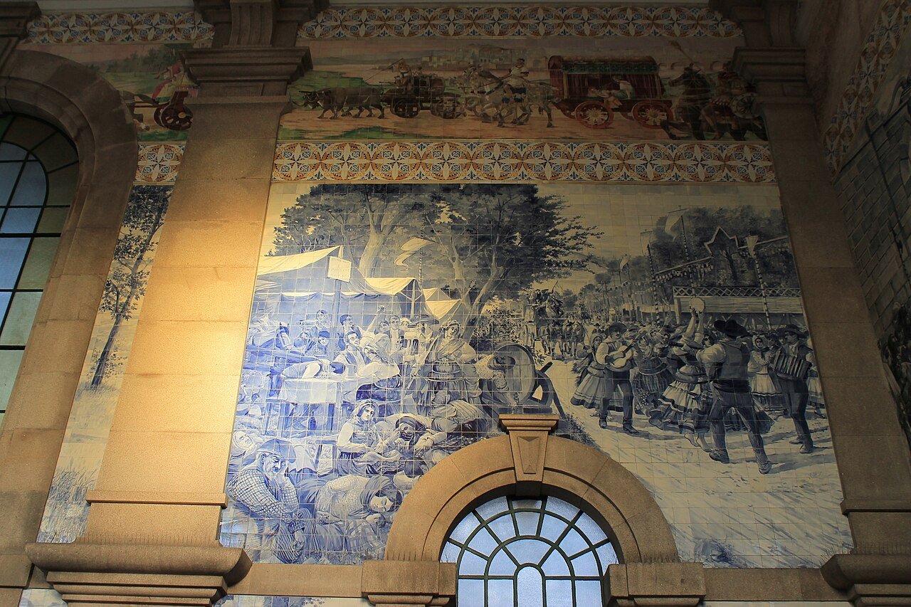 Blue-and-white azulejo tile panel in the entrance hall of São Bento railway station in Porto, showing a historical scene above an arched window