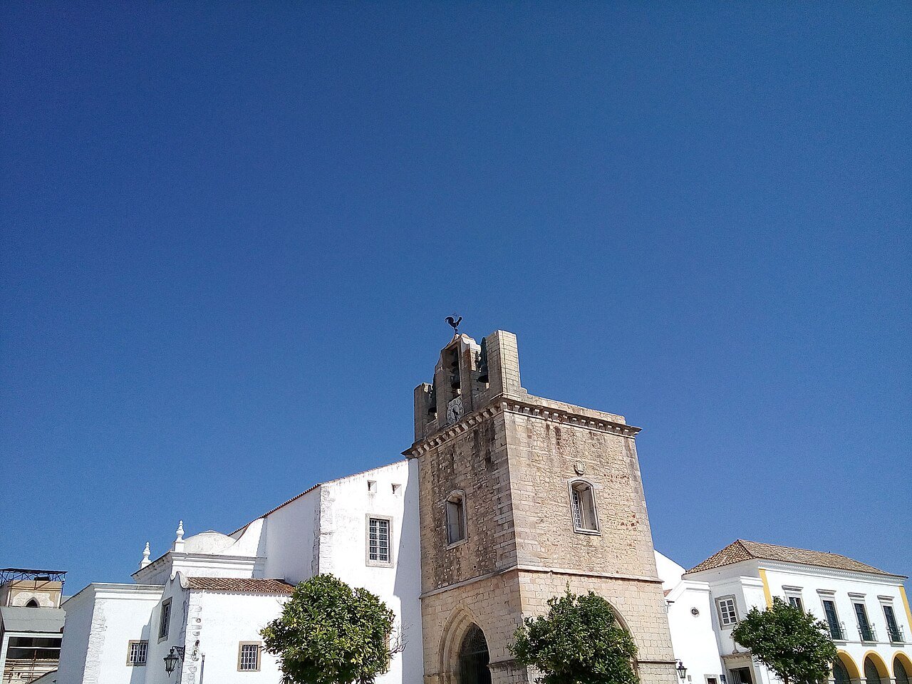 Faro Cathedral (Sé de Faro): a whitewashed church front beside a square medieval bell tower under a blue sky