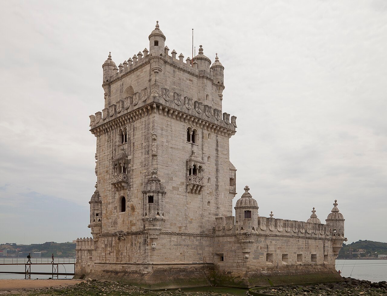 The Tower of Belém in Lisbon: a pale limestone fortress tower with corner watchtowers on the bank of the Tagus